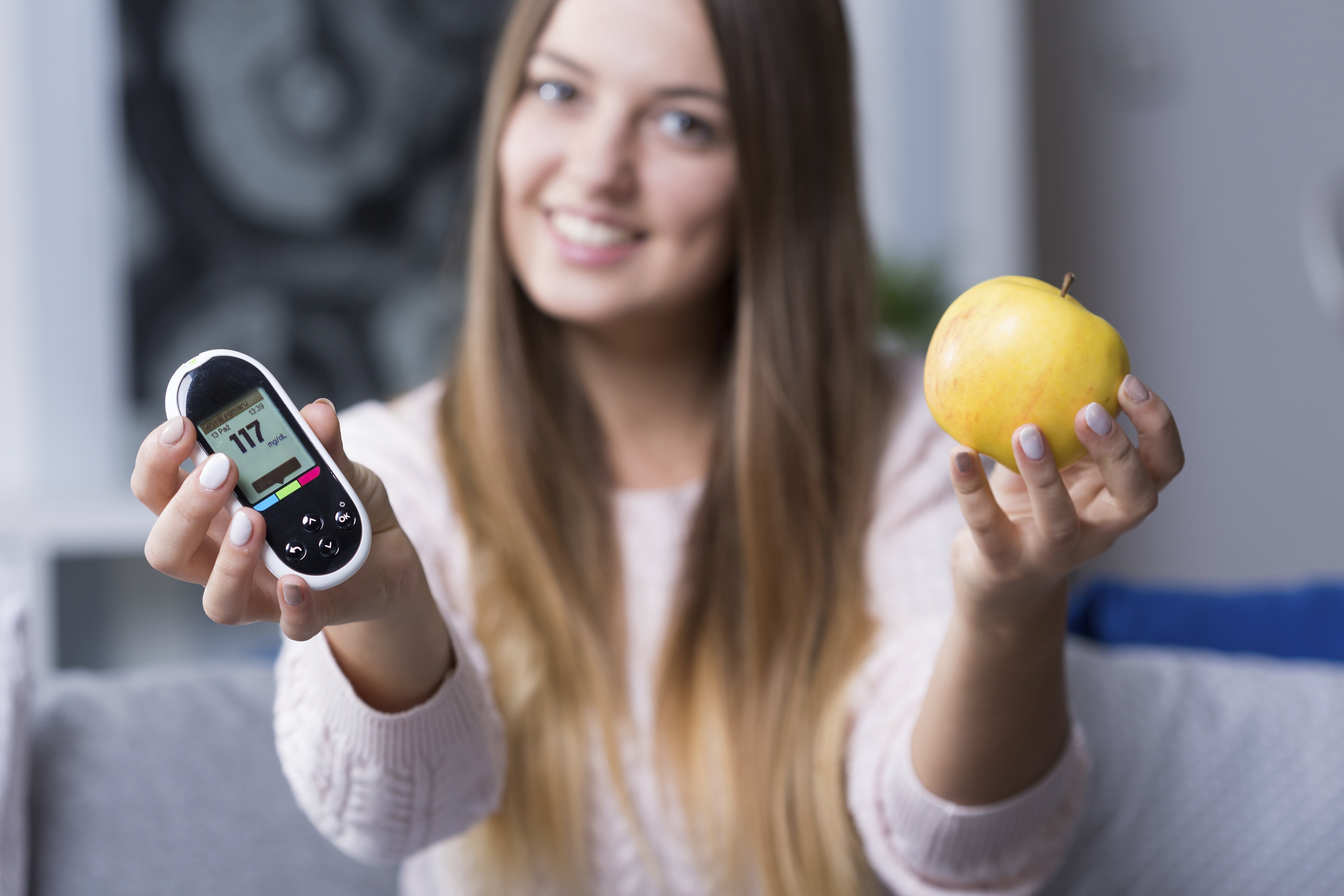 Young diabetic woman holding glucometer and apple